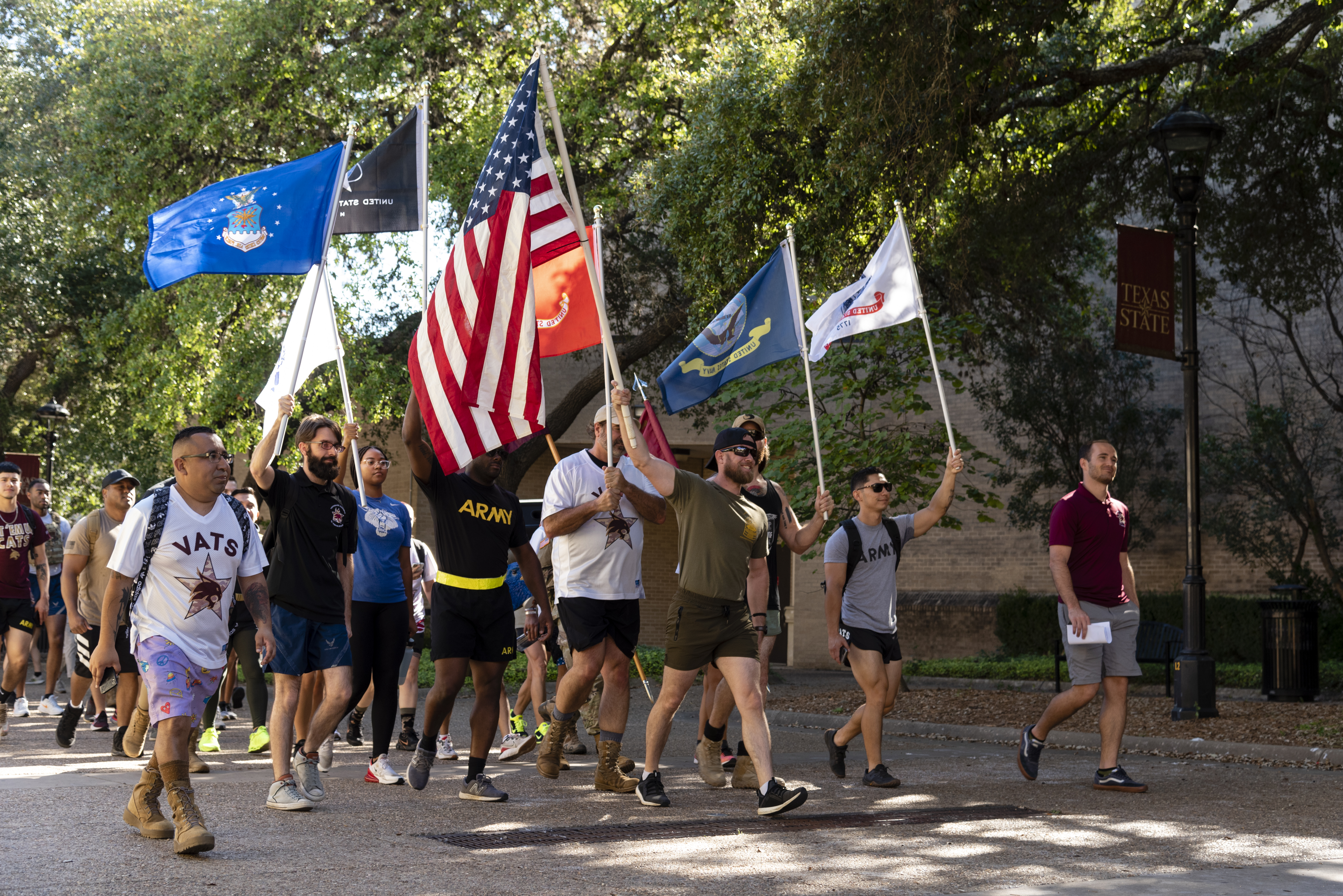 Texas State University student Veterans in plain clothes walking carring various American and American military flags.