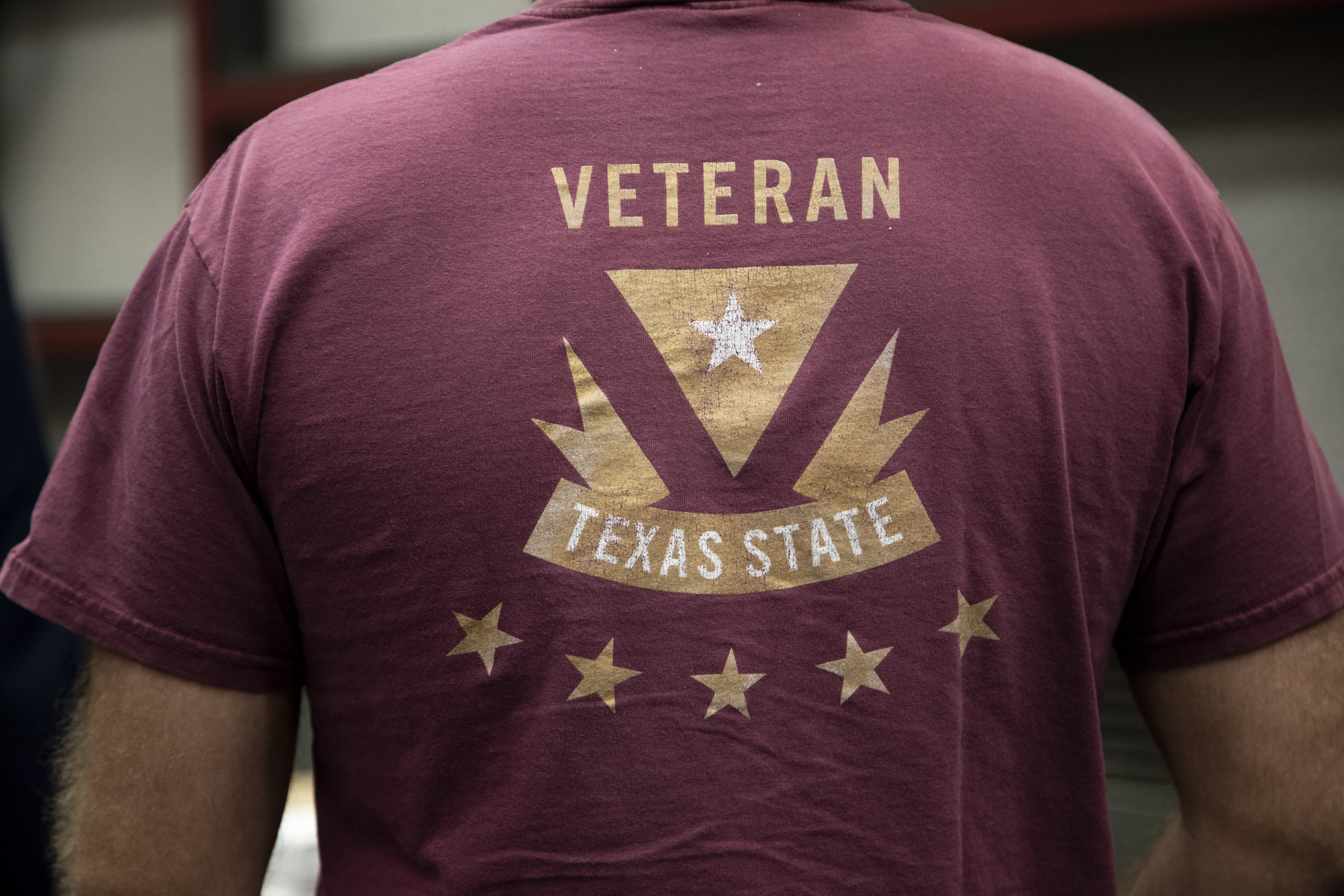 Close-up image of a person's back wearing a red t-shirt that says VETERAN TEXAS STATE.